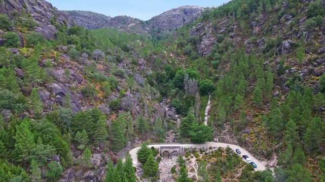 Horizontal aerial drone shot of Cascata do Arado waterfall surrounded by lush green rock formations and clear water pools in Peneda-Geres National Park, Portugal.