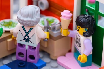 Naklejka premium Tambov, Russian Federation - January 27, 2026 A close-up shot of a Lego girl minifigure holding an ice cream cone while visiting a grandmother in a kitchen.