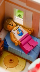 Naklejka premium Tambov, Russian Federation - February 11, 2026 A close-up shot of a Lego female minifigure resting on a bed in a bedroom.