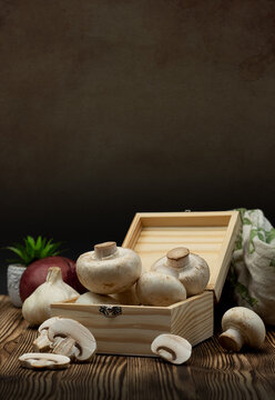 Fresh White Button Mushrooms in Wooden Crate with Garlic and Onion on Rustic Wooden Table
