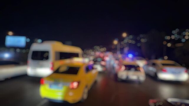 A blurry video showing a major traffic jam on Altinyol Street in Izmir after a midnight accident, with flashing police lights and drivers standing outside their vehicles in frustration.