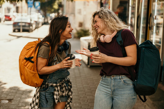 Happy young women friends traveling city street laughing