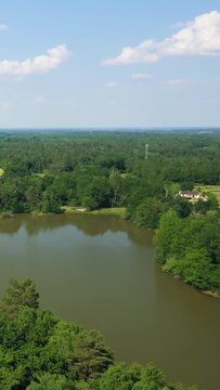 Vertical 9:16 aerial video of Etang du Gue l'Eveque, showing a tranquil pond surrounded by dense green forest near Dampierre-en-Burly, Centre-Val de Loire, France.