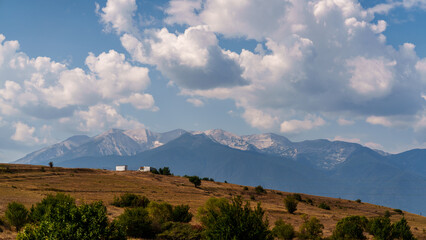Obraz premium Rural fields and mountains under cloudy sky
