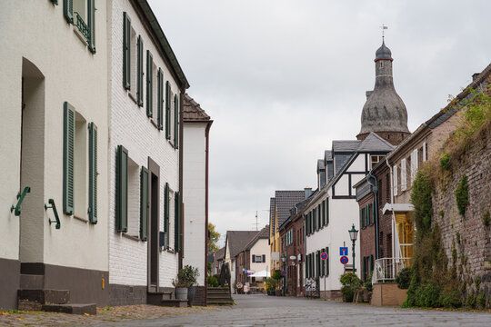 Historic houses line a narrow street leading toward a Juddeturm tower in Zons