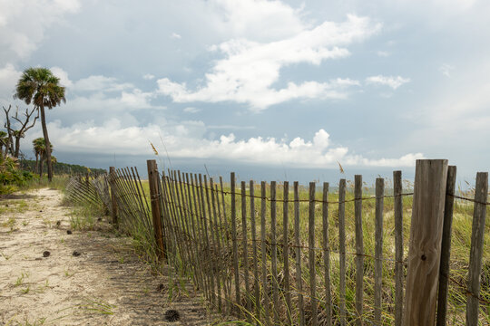 Ocean view with wooden fence along sandy path at beach in daylight