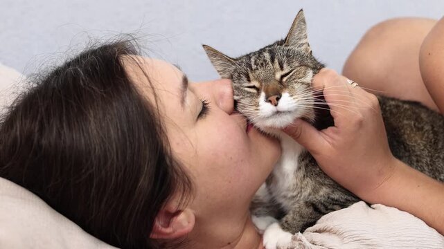 Young woman affectionately nuzzles cats cheek and enjoys its familiar scent. Happy feline accepts close contact showing deep attachment and trust.