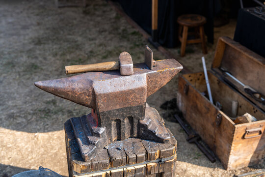Traditional steel anvil with a hammer resting on its surface. Blacksmithing equipment, craftsmanship, forging, skilled trades and traditional manufacturing.
