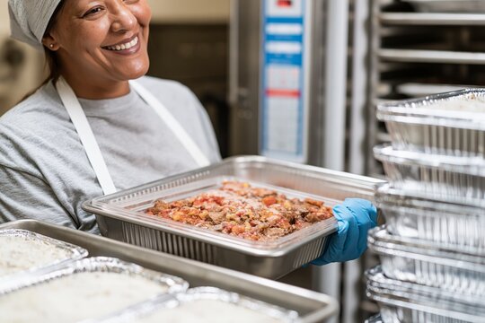 Nonprofit kitchen worker holding frozen prepared meal tray for donation