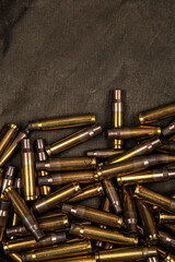 Spent brass bullet casings pile on dark fabric texture with copy space. © solidmaks