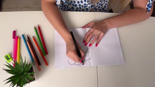 High-angle close-up of hands with bright pink manicure cutting long narrow strips from squared graph paper using scissors on pale tabletop, with hand, scissor, cutting, paper detail