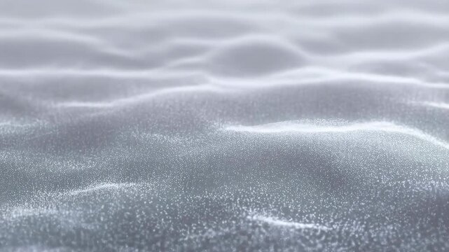 Small white particles flow and shift to form smooth wave-like patterns on a soft gray surface. Smooth wave movement creates soft glow and visible depth.