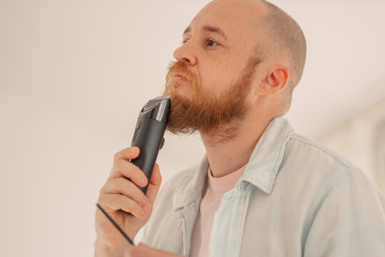 Man adjusting the length setting of a beard trimmer