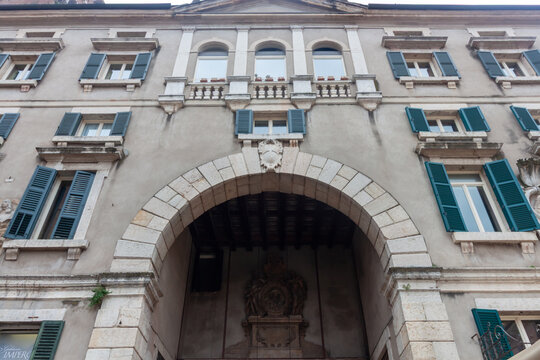VERONA, ITALY - OCTOBER 23, 2024: Low angle view of historical stone archway and facade of traditional European building in Verona