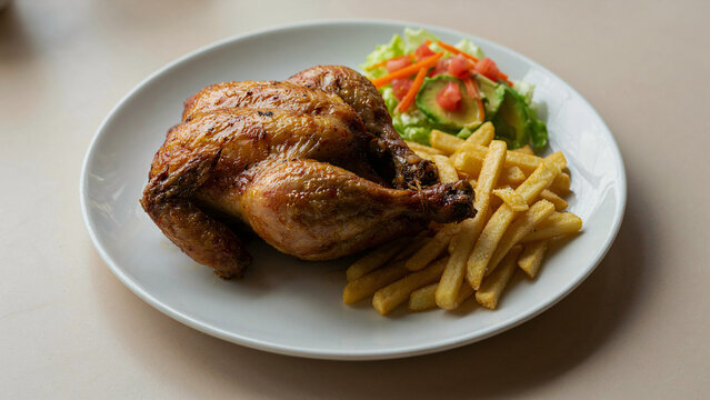 Pollo a la brasa peruano servido con papas fritas y ensalada fresca de lechuga, tomate y palta