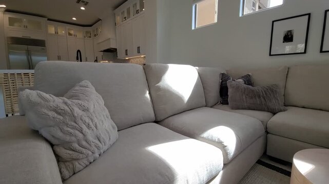 Bright modern living room with beige sofa and open kitchen