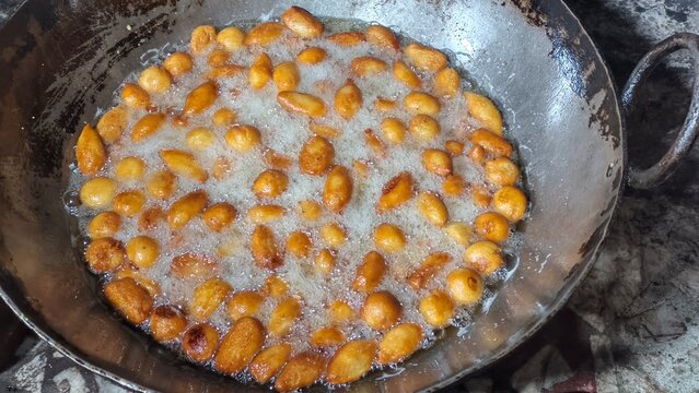 Deep frying traditional Indian sweet pantua in boiling oil pan