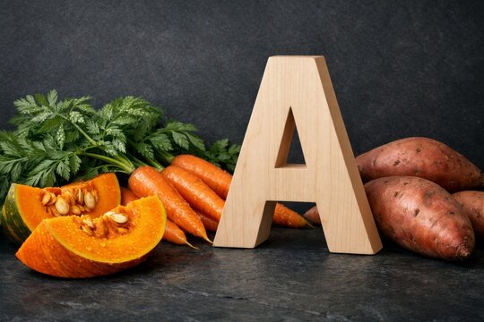 Wooden letter a with pumpkin carrots sweet potatoes and parsley vitamin a vegetables arrangement for healthy food background