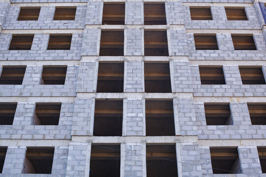Facade of an unfinished residential building made of concrete blocks with empty windows