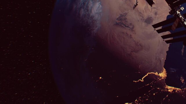 The Earth appears from space showing cities lit up at night. The International Space Station is in the foreground. This shows the planet from a distance with lights below.