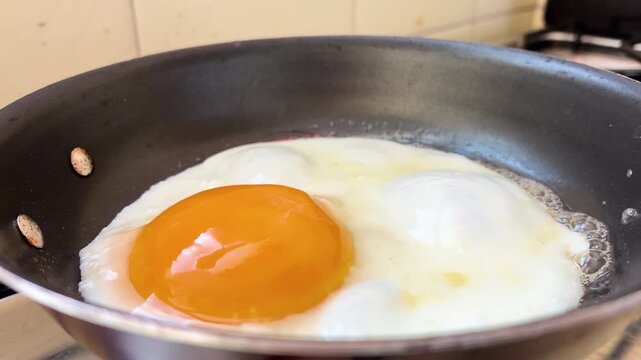 Close up of fried egg cooking in a frying pan