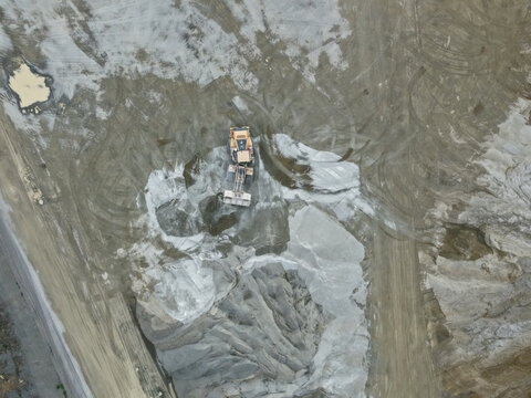 Montrose, Australia - 26 August 2026: Aerial view of Boral Montrose quarry featuring a yellow bulldozer working on piles of crushed rock and gravel with tire tracks visible in the dusty ground.
