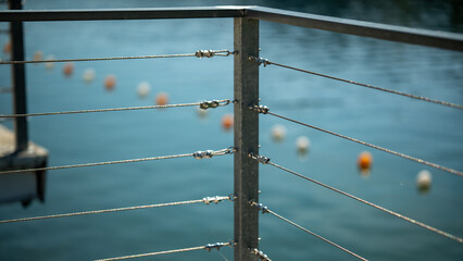 Railing at the edge of the dock near the water with floating buoys in the background © Stas