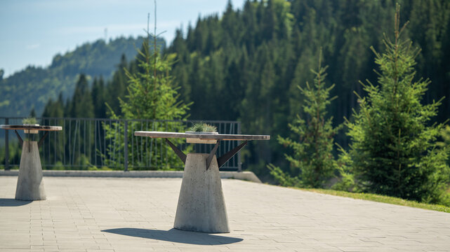 Tables are set outside under the sun with trees and mountains in the background during the day