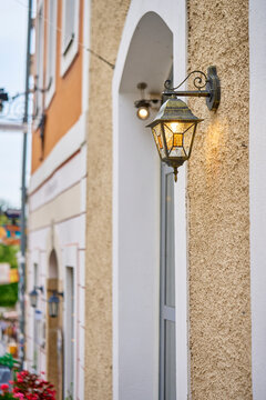 Glowing outdoor wall lantern mounted beside arched doorway on building facade