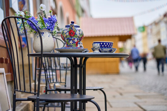 Ceramic tea set with patterned cups, plates and flower vase displayed on table outdoors