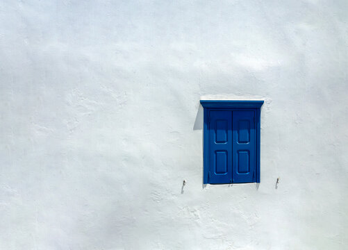 Mykonos white wall with traditional blue window shutters