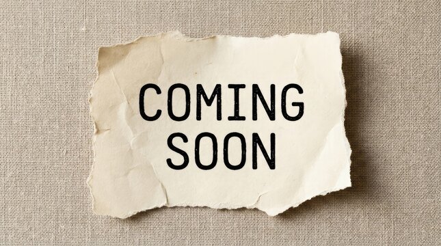 Creased paper announcement reading coming soon on textured fabric background with neutral fabric backdrop under even lighting crumpled aged piece