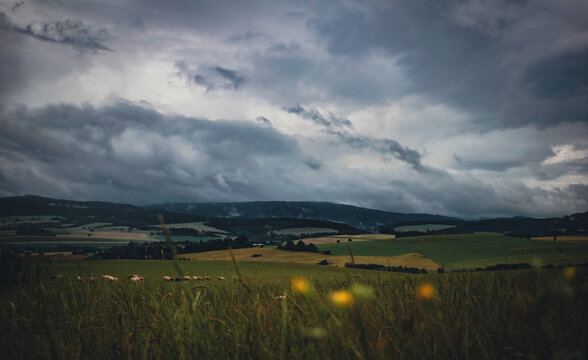 Rolling Green Hills and Fields Under Dramatic Storm Clouds