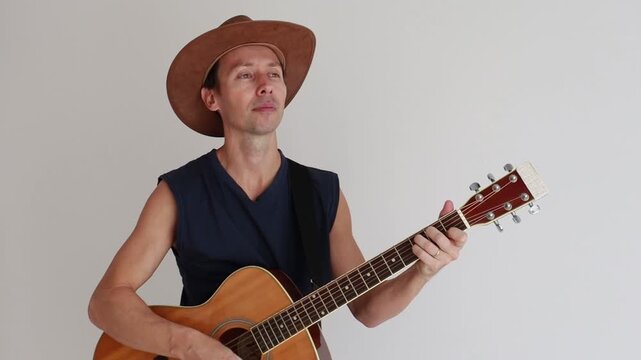 homem sertanejo usando chap&eacute;u de vaqueiro e tocando viol&atilde;o acustico 