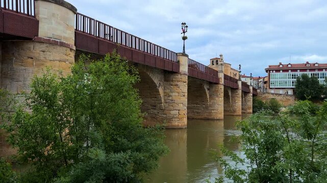Ebro River in Miranda de Ebro town, Burgos, Spain. Historic stone bridge view and city skyline under cloudy sky. High quality 4k footage