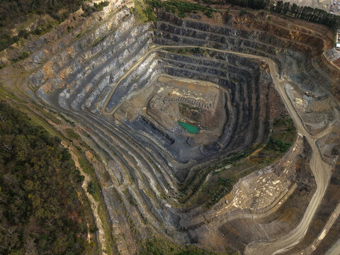 Montrose, Victoria, Australia - 26 August 2026: Aerial view of Boral Montrose quarry with deep terraced excavation pits, rocky slopes, and a small turquoise pool surrounded by forest.