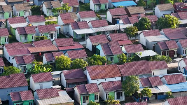 Rows of small suburban houses packed closely together in a sunny residential neighborhood area