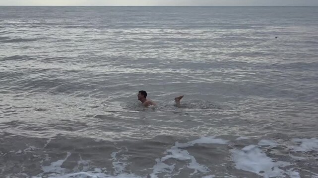 Young man floats effortlessly in the mineral-rich waters of the Dead Sea in Jordan, experiencing the natural buoyancy and calm surface of the hypersaline waters