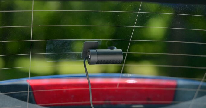 Interior view of a car looking through the back window with a dashcam mounted on the glass for safety, recording traffic and events