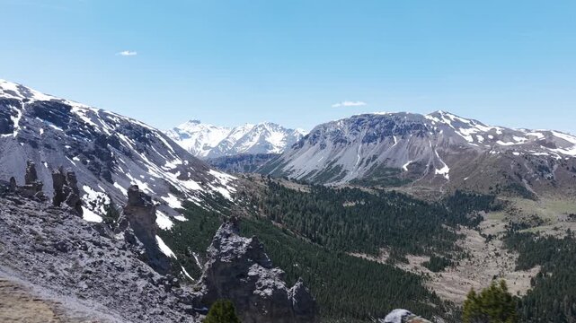 Stunning aerial view of Il Jalet mountain ridge in the Swiss Alps. Majestic peaks covered in snow and a green valley with a pine forest