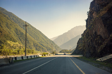 Naklejka premium Georgian mountain road through rocky canyon and green valley, scenic highway in Caucasus, travel adventure, transportation infrastructure, road trip and driving.