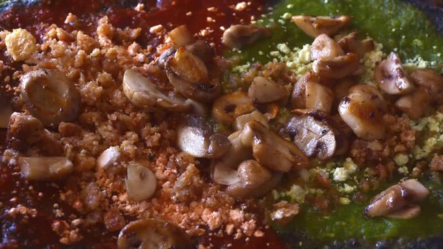 Extreme Close-Up of Traditional Mexican picaditas topped with saut&eacute;ed mushrooms, crumbled queso cotija, pork rinds and red and green salsa