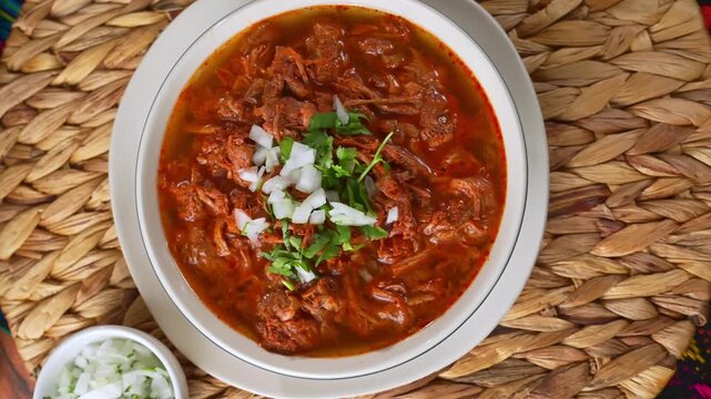 Overhead view of authentic Mexican Birria de res soup with red chili broth