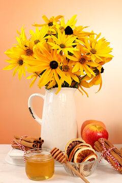 Autumn banner with a beautiful bouquet of rudbeckia in a vase, honey, apples, dried orange, cinnamon and star anise on an elegant background, autumn greeting and gratitude concept, cozy composition