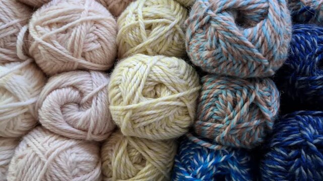 Soft yarn skeins are piled together in neutral colors, knitting hobby, cozy texture, handmade craft, textile materials.