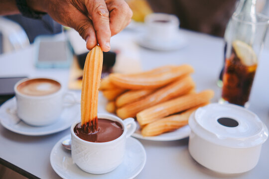Hand Dipping Churro into Chocolate Sauce - Traditional Spanish Breakfast Street Food