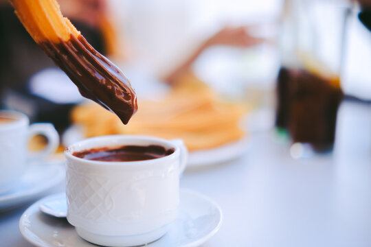 Hand Dipping Churro into Chocolate Sauce - Traditional Spanish Breakfast Street Food