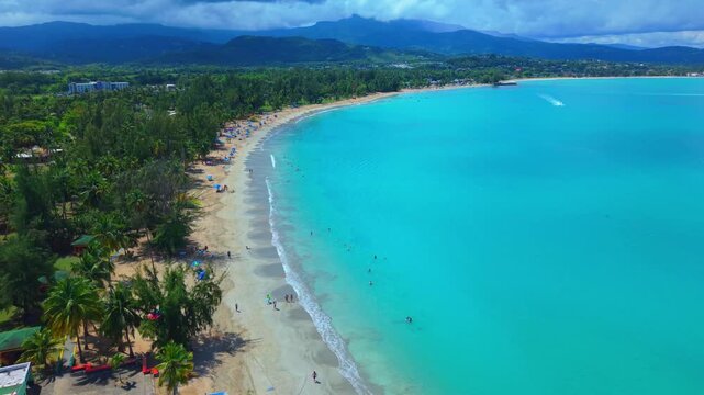 Establishing aerial shot starting over the famous Luquillo Kiosks (Kioskos de Luquillo) and extending towards the palm-fringed shoreline and ocean waves.