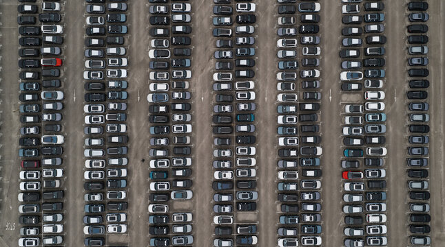 Spain - 22 August 2026: Aerial view of new cars parked in a parking lot waiting to be transported for export, arranged in neat rows on asphalt.