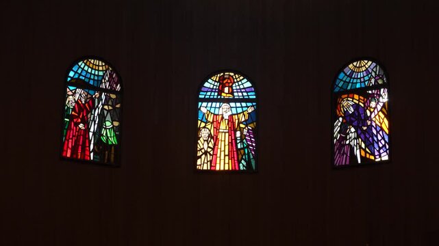 Cinematic panning view, stained glass windows depicting biblical figures inside the Memorial Church of Moses on Mount Nebo near Madaba, Jordan, a major Christian pilgrimage site